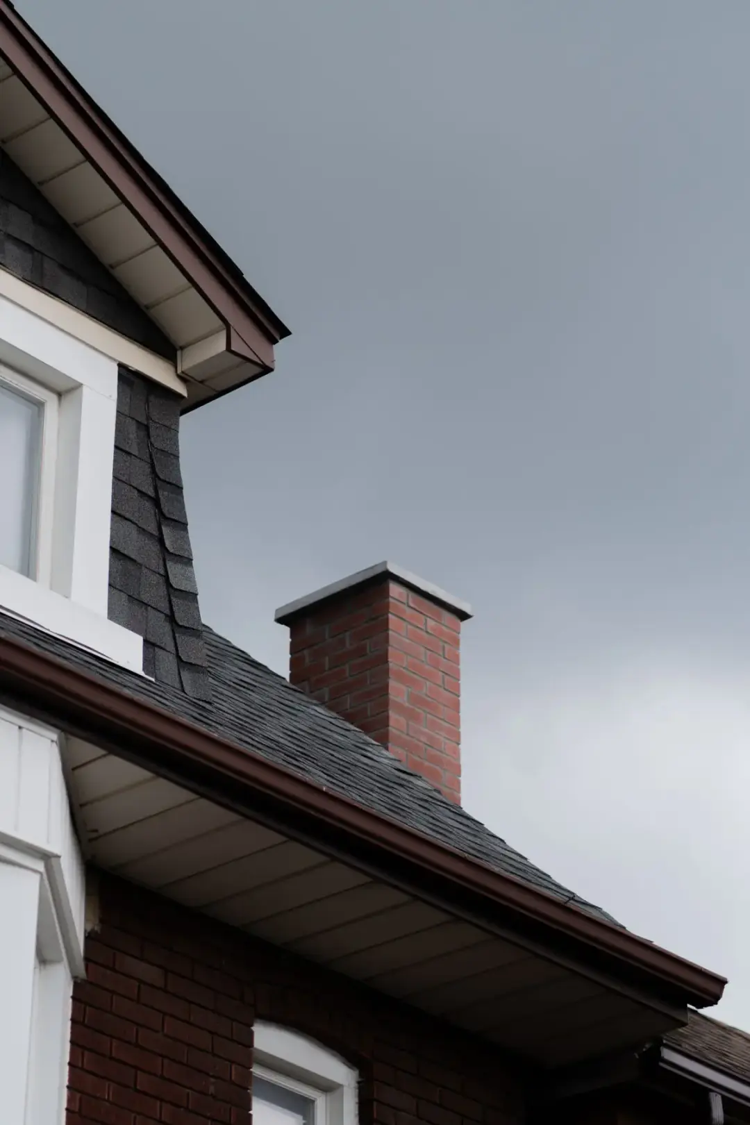 Asphalt shingles meeting a brick chimney